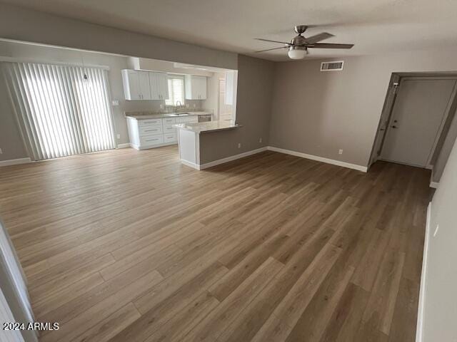 unfurnished living room with ceiling fan and dark wood-type flooring