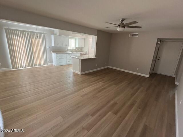 unfurnished living room with ceiling fan, wood-type flooring, and sink