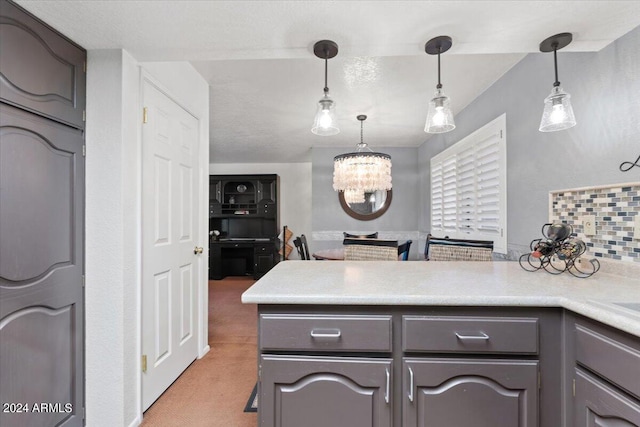 kitchen with kitchen peninsula, carpet, a chandelier, gray cabinetry, and decorative light fixtures