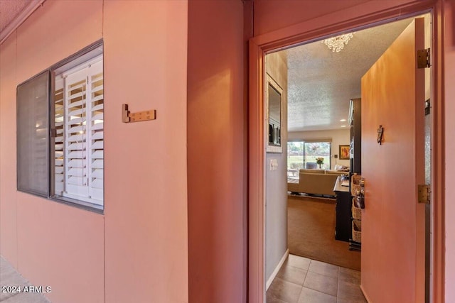 hallway with a textured ceiling and light colored carpet