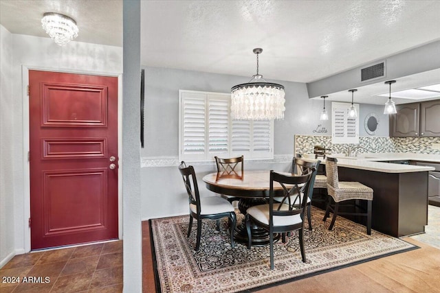 dining room with an inviting chandelier and a textured ceiling