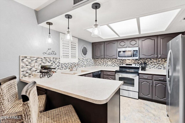 kitchen featuring tasteful backsplash, appliances with stainless steel finishes, decorative light fixtures, and kitchen peninsula