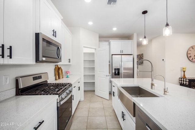 kitchen with decorative light fixtures, stainless steel appliances, light stone countertops, white cabinets, and light tile patterned floors