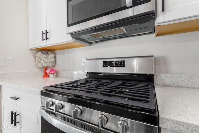 kitchen featuring white cabinets, stainless steel appliances, and light stone countertops