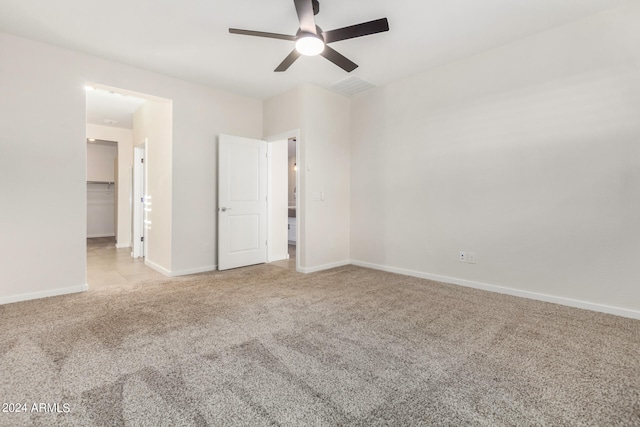 unfurnished bedroom with ceiling fan, light colored carpet, a closet, and a walk in closet