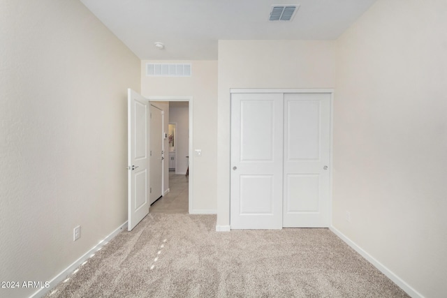 unfurnished bedroom featuring light carpet and a closet