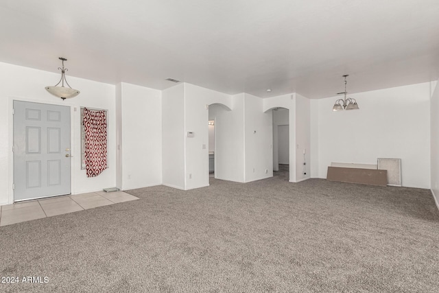 unfurnished living room featuring light carpet and a notable chandelier