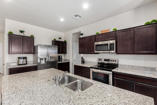 36454 W Picasso St, Maricopa, AZ 85138 - kitchen with appliances with stainless steel finishes, a sink, dark brown cabinets, recessed lighting, and light stone counters