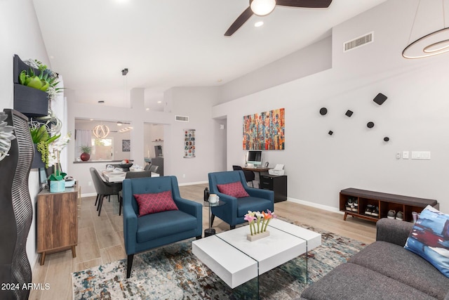 living room with a towering ceiling, light wood-type flooring, and ceiling fan