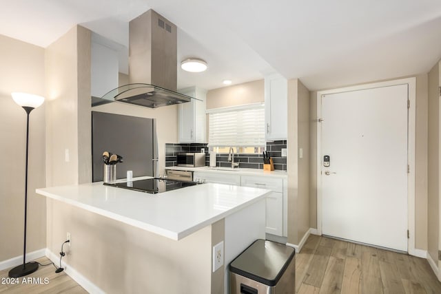 kitchen featuring white cabinetry, sink, light hardwood / wood-style flooring, island range hood, and appliances with stainless steel finishes