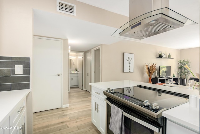 kitchen featuring island exhaust hood, light wood-type flooring, white cabinetry, and stainless steel range with electric cooktop