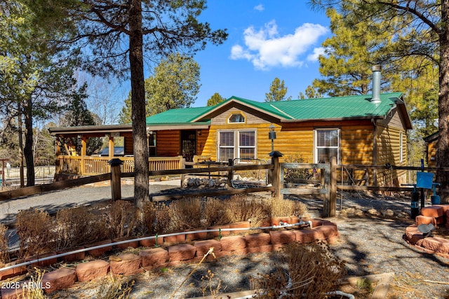 view of front of property featuring metal roof and fence