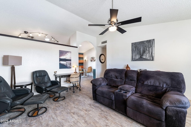 living room with a textured ceiling, ceiling fan, and vaulted ceiling