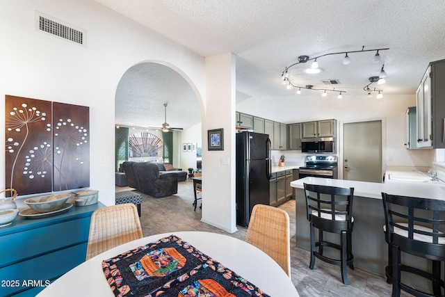 dining area featuring a textured ceiling, vaulted ceiling, ceiling fan, and sink