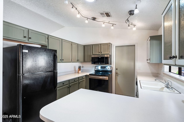 kitchen featuring sink, kitchen peninsula, a textured ceiling, lofted ceiling, and appliances with stainless steel finishes