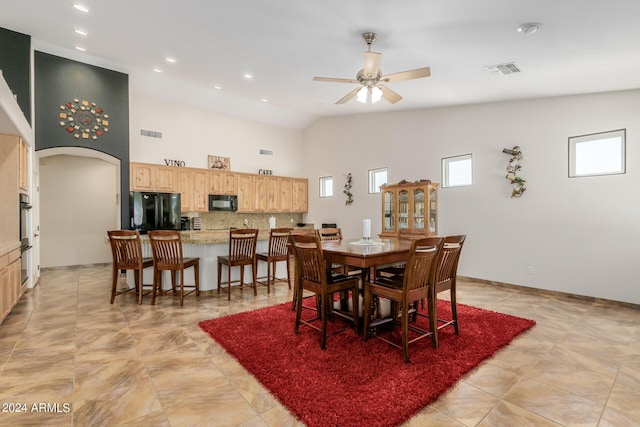 tiled dining room with ceiling fan and high vaulted ceiling