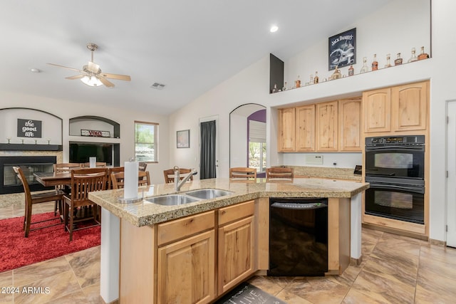 kitchen with sink, an island with sink, black appliances, and vaulted ceiling