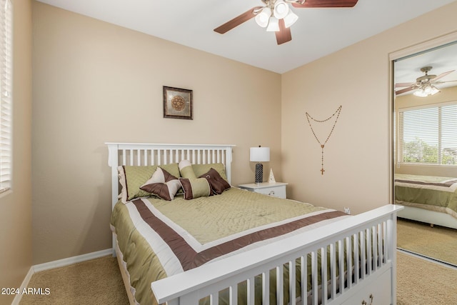 bedroom with ceiling fan, light carpet, and a closet