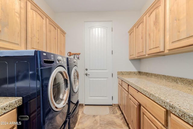 clothes washing area featuring cabinets and washing machine and clothes dryer