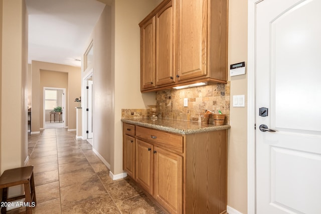 bar with light stone countertops and decorative backsplash