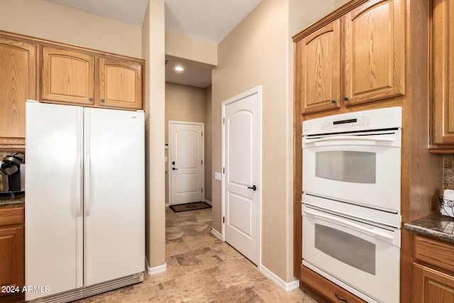 kitchen with dark stone counters and white appliances