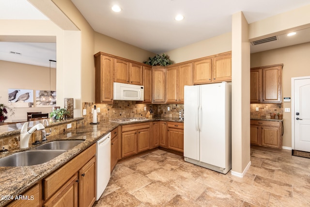 kitchen featuring dark stone counters, decorative backsplash, white appliances, and sink