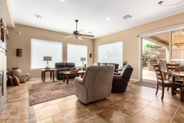 living room featuring ceiling fan and a tile fireplace