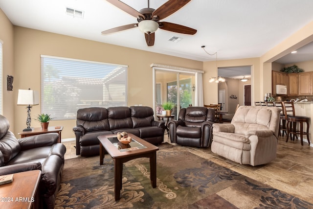 living room with ceiling fan with notable chandelier