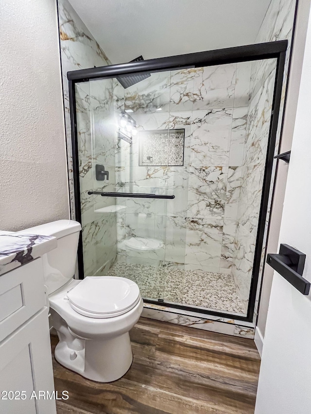 bathroom featuring vanity, hardwood / wood-style flooring, toilet, and a shower with shower door