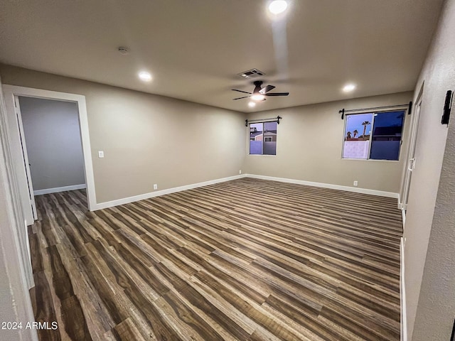 empty room with ceiling fan and dark hardwood / wood-style flooring