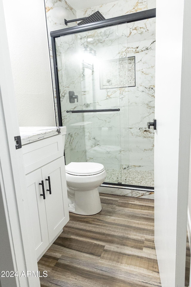 bathroom with a shower with door, vanity, wood-type flooring, and toilet