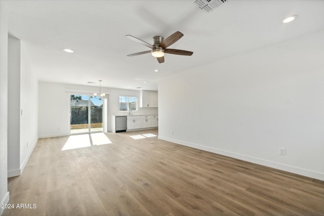 unfurnished living room with ceiling fan with notable chandelier, light hardwood / wood-style floors, and sink