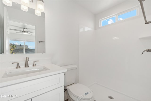 bathroom featuring walk in shower, ceiling fan, vanity, and toilet