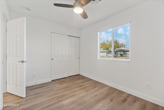 unfurnished bedroom with a closet, light hardwood / wood-style floors, and ceiling fan