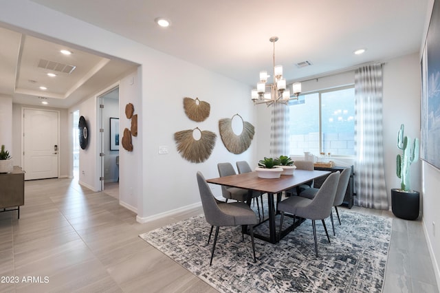 dining area with a raised ceiling and a chandelier