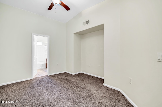 carpeted spare room with ceiling fan and vaulted ceiling