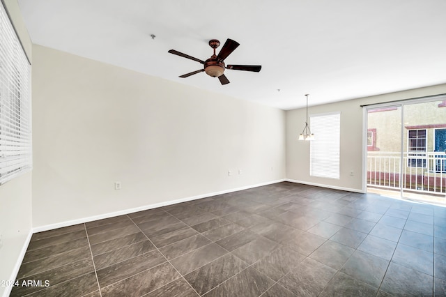 spare room with ceiling fan with notable chandelier and dark tile patterned flooring