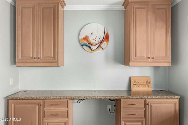 kitchen with stone countertops, crown molding, and built in desk