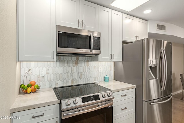 kitchen with stainless steel appliances, white cabinets, visible vents, and backsplash