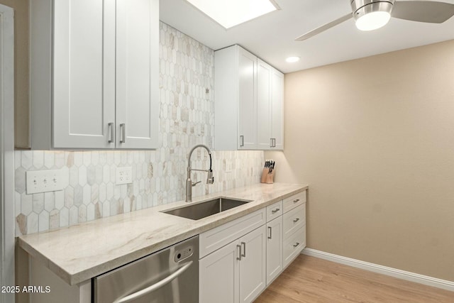 kitchen with ceiling fan, light stone counters, a sink, decorative backsplash, and dishwasher