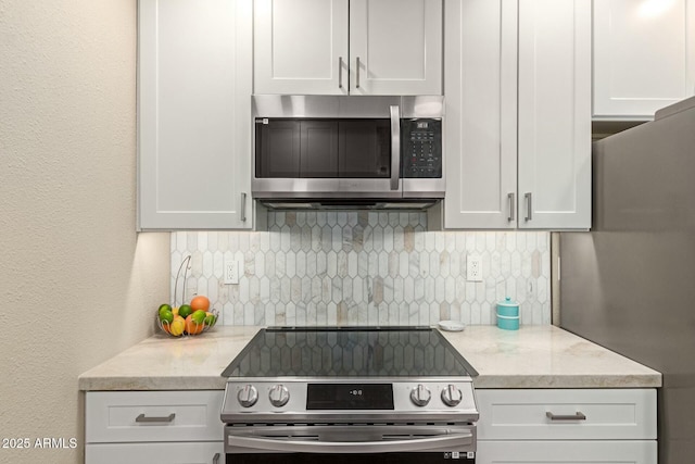 kitchen featuring white cabinets, light stone countertops, tasteful backsplash, and stainless steel appliances