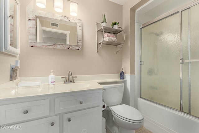 bathroom featuring visible vents, combined bath / shower with glass door, vanity, and toilet