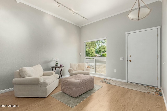 living area with crown molding, track lighting, baseboards, and wood finished floors