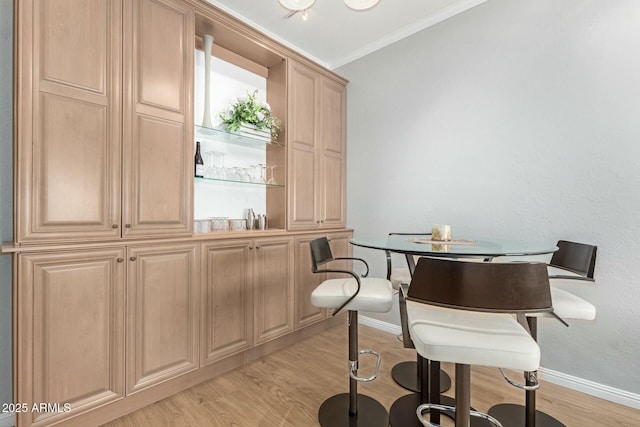 dining room with light wood-type flooring, baseboards, and crown molding