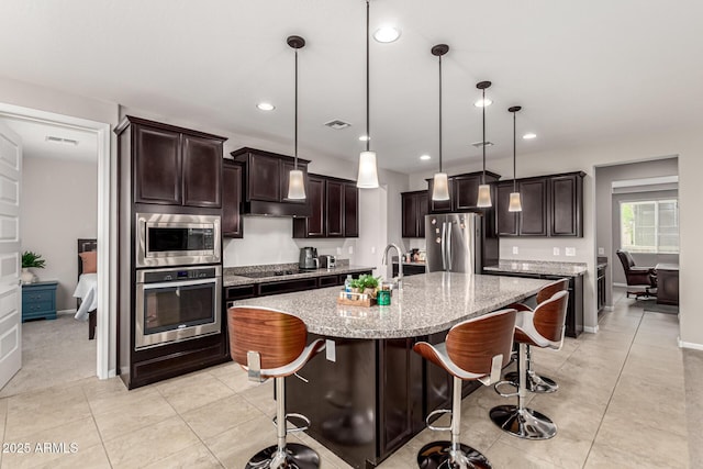 14727 W Pasadena Ave, Litchfield Park, AZ 85340 - kitchen with stainless steel appliances, dark brown cabinets, light stone counters, a kitchen bar, and recessed lighting
