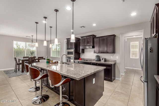 14727 W Pasadena Ave, Litchfield Park, AZ 85340 - kitchen with stainless steel appliances, a sink, baseboards, dark brown cabinets, and light stone counters