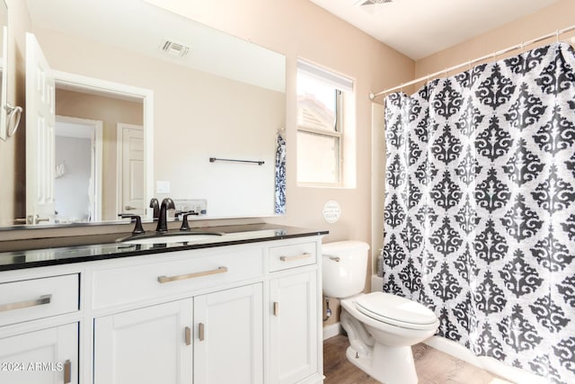 bathroom featuring wood-type flooring, vanity, toilet, and walk in shower