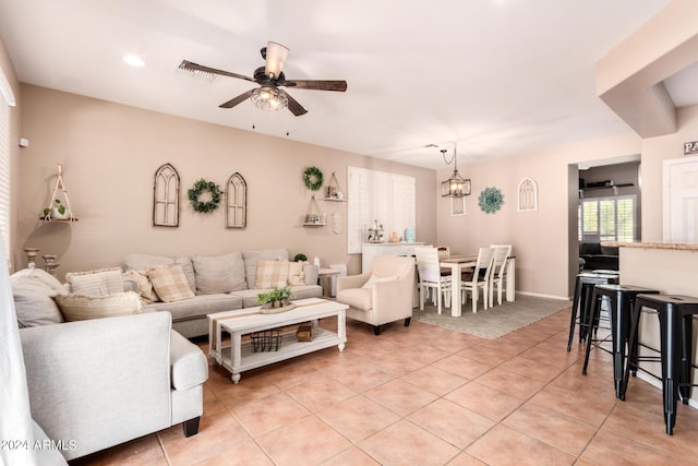 tiled living room featuring ceiling fan with notable chandelier