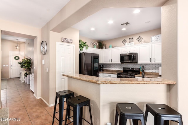 kitchen with kitchen peninsula, a kitchen bar, white cabinetry, and stainless steel appliances