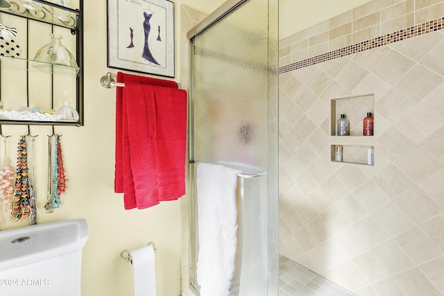 bathroom with toilet and a shower with shower door